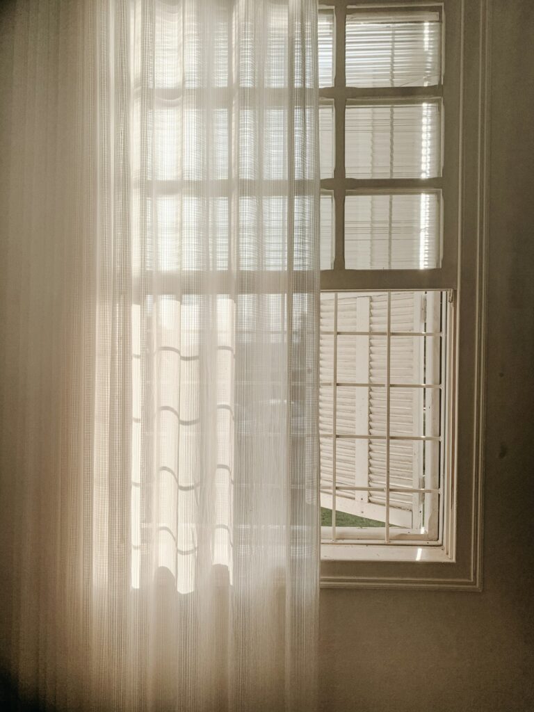 Ventana con cortina blanca translúcida y luz cálida entrando